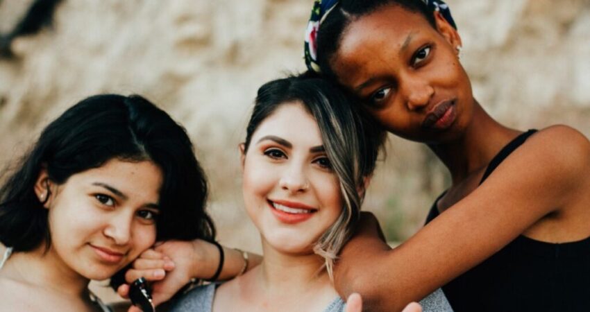 Three women with different skin types pose for a picture.