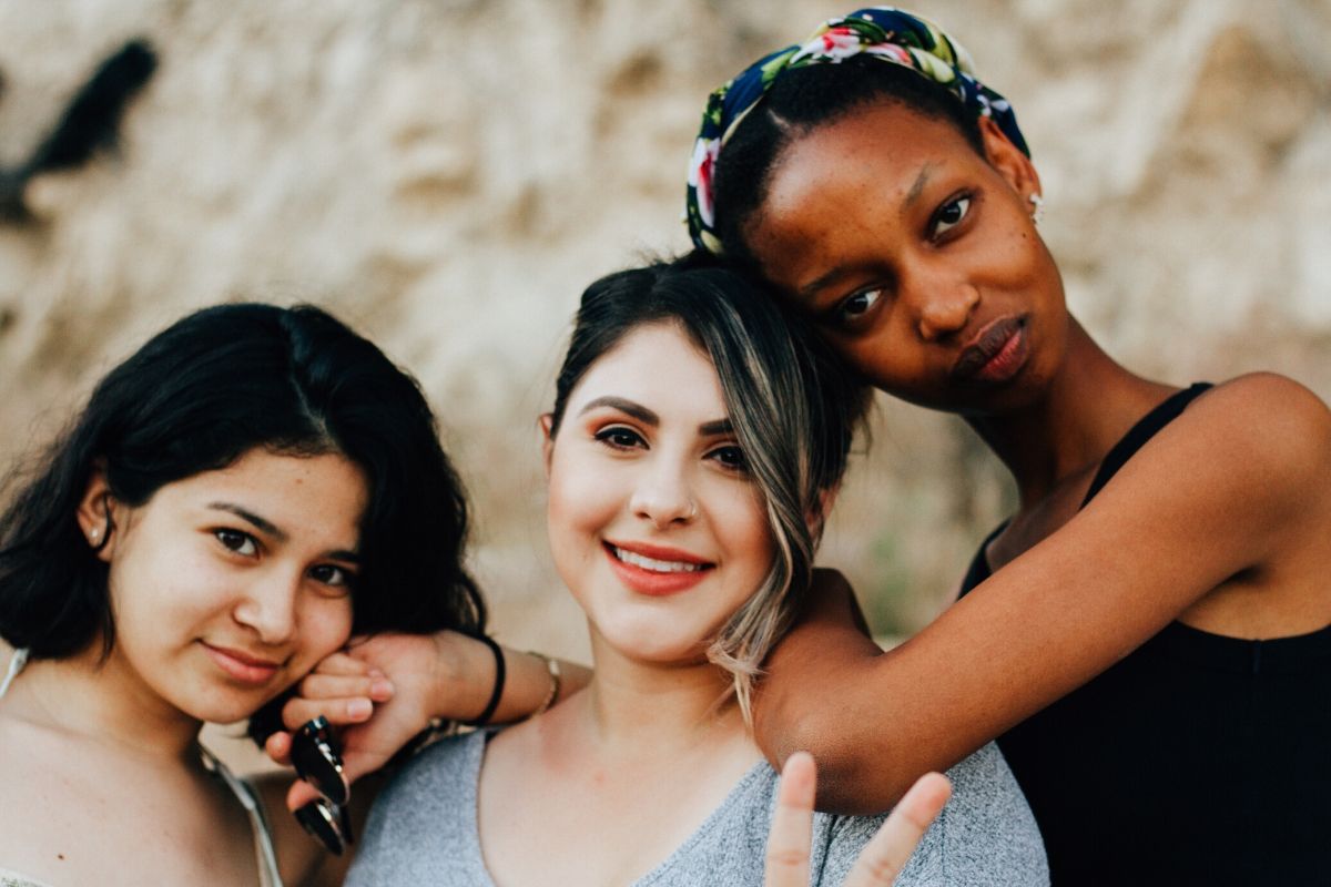 Three women with different skin types pose for a picture.