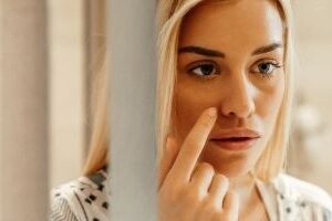 Woman staring her face in front of the mirror