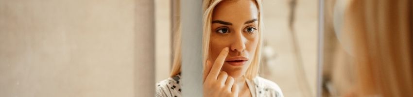 Woman staring her face in front of the mirror