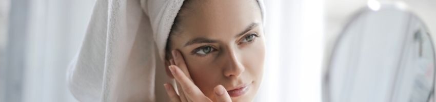 Woman after shower examining skin in the mirror and wondering shy her skin is darker than before