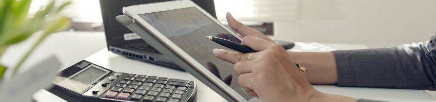 a table with a calculator with the hand of a man calculating the cost