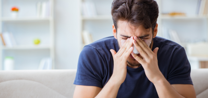 A man keeping his head down while holding his bandaged nose.