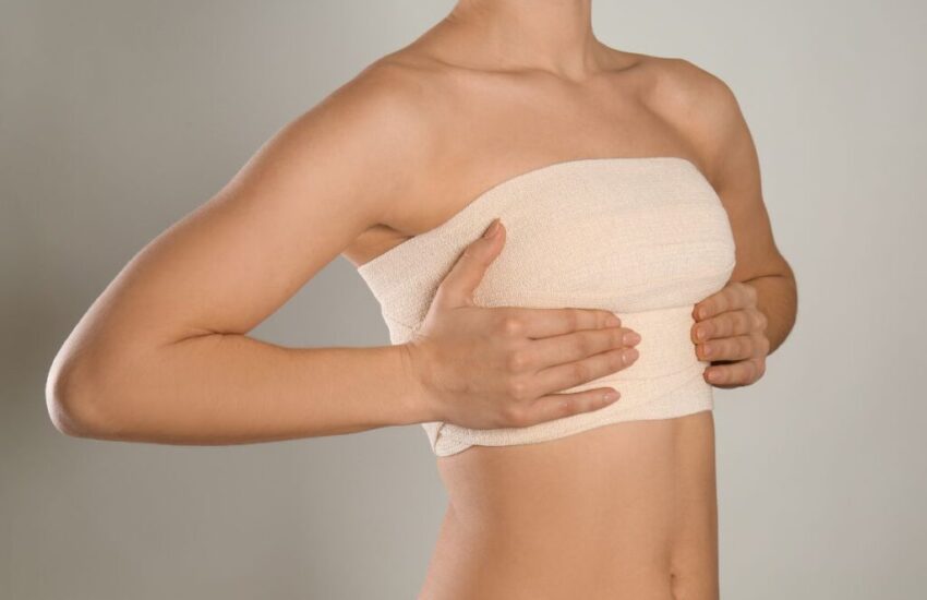 A woman touches and feels her breast after undergoing a breast lift procedure.