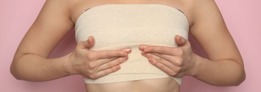 A woman touches her breast after breast lift procedure.